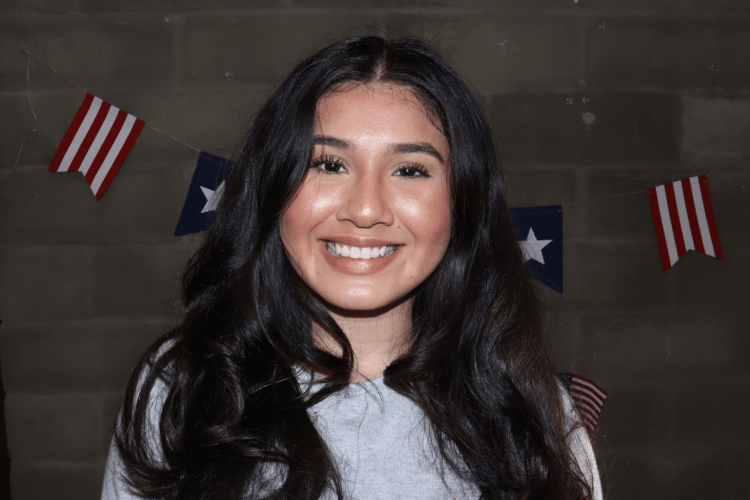A portrait of a woman indoors, in front of a red, white, and blue banner